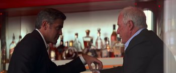 Movie still from “Ocean's Thirteen” (2007), directed by Steven Soderbergh – Two men in suits are sitting at a bar; Medium shot, Over the shoulder angle