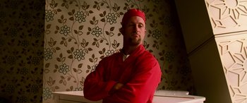 Movie still from “Ocean's Thirteen” (2007), directed by Steven Soderbergh – A man in a red coat and a red hat is posing for a picture; Close Up shot, Low angle