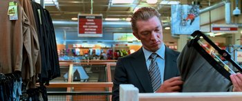 Movie still from “Ocean's Thirteen” (2007), directed by Steven Soderbergh – A man in a suit and tie sitting at a table in a store; Medium shot, Over the shoulder angle