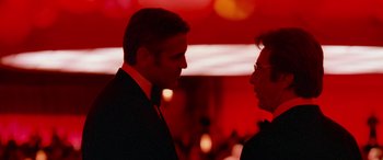Movie still from “Ocean's Thirteen” (2007), directed by Steven Soderbergh – Two men in suits talking to each other in front of a red background; Close Up shot, Over the shoulder angle
