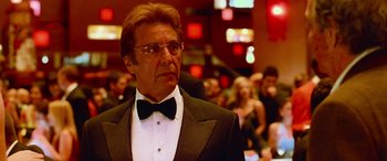 Movie still from “Ocean's Thirteen” (2007), directed by Steven Soderbergh – A man in a suit and bow tie in front of a group of people; Close Up shot, Low angle