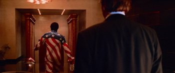 Movie still from “Ocean's Thirteen” (2007), directed by Steven Soderbergh – A man in a suit and american flag shirt walking down a hall way; Medium shot, Low angle