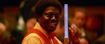 Movie still from “Ocean's Thirteen” (2007), directed by Steven Soderbergh – A man in a red vest holding up a blue stick; Close Up shot, Low angle