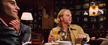 Movie still from “Ocean's Twelve” (2004), directed by Steven Soderbergh – A man sitting at a table with a glass of orange juice; Medium shot, Over the shoulder angle