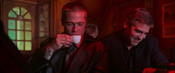 Movie still from “Ocean's Twelve” (2004), directed by Steven Soderbergh – A man drinking a cup of coffee while wearing a leather jacket; Medium shot, Low angle