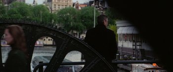 Movie still from “Ocean's Twelve” (2004), directed by Steven Soderbergh – A man standing on the side of a bridge looking out over the water; Medium shot, Over the shoulder angle