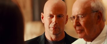 Movie still from “Ocean's Twelve” (2004), directed by Steven Soderbergh – A man with a bald head and a black jacket; Close Up shot, Over the shoulder angle