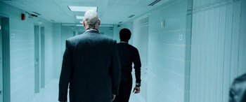 Movie still from “Ocean's Twelve” (2004), directed by Steven Soderbergh – Two men in suits are walking down a hallway; Medium shot, Over the shoulder angle