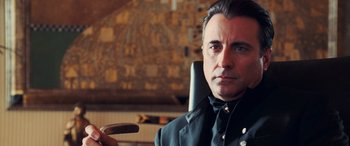 Movie still from “Ocean's Twelve” (2004), directed by Steven Soderbergh – A person sitting in a chair holding a remote; Close Up shot, Over the shoulder angle