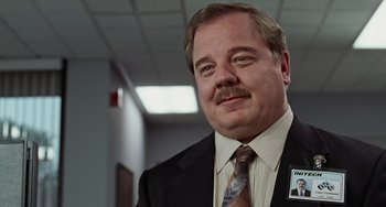 Movie still from “Office Space” (1999), directed by Mike Judge – A person wearing a suit and tie; Close Up shot, Low angle