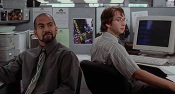 Movie still from “Office Space” (1999), directed by Mike Judge – Two men sitting in an office chair in front of a computer screen; Medium shot, Over the shoulder angle