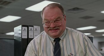 Movie still from “Office Space” (1999), directed by Mike Judge – An older man wearing glasses and a striped shirt; Close Up shot, Low angle