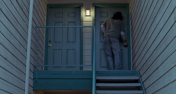 Movie still from “Office Space” (1999), directed by Mike Judge – A person walking down the stairs of a house; Wide shot, Low angle