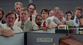 Movie still from “Office Space” (1999), directed by Mike Judge – A group of people sitting in an office cubicle; Wide shot, Low angle