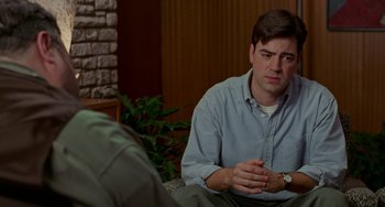 Movie still from “Office Space” (1999), directed by Mike Judge – A man sitting on the ground in front of another man; Medium shot, Over the shoulder angle