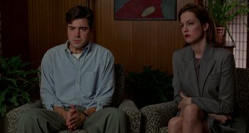 Movie still from “Office Space” (1999), directed by Mike Judge – A man and a woman sitting next to each other on a couch; Medium shot, Over the shoulder angle