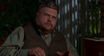 Movie still from “Office Space” (1999), directed by Mike Judge – A person wearing glasses and a vest; Close Up shot, Over the shoulder angle