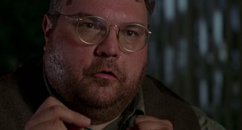 Movie still from “Office Space” (1999), directed by Mike Judge – A person wearing glasses and a jacket; Close Up shot, Low angle