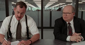 Movie still from “Office Space” (1999), directed by Mike Judge – Two men sitting at a table in an office setting; Medium shot, Over the shoulder angle
