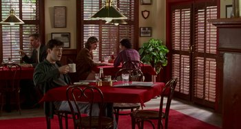 Movie still from “Office Space” (1999), directed by Mike Judge – A group of people sitting at a table in a restaurant; Wide shot, Over the shoulder angle