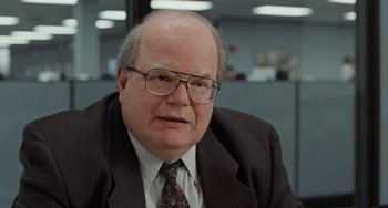 Movie still from “Office Space” (1999), directed by Mike Judge – An older man wearing glasses and a suit and tie; Close Up shot, Over the shoulder angle