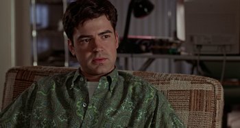 Movie still from “Office Space” (1999), directed by Mike Judge – A person sitting on a couch wearing a shirt; Close Up shot, Over the shoulder angle