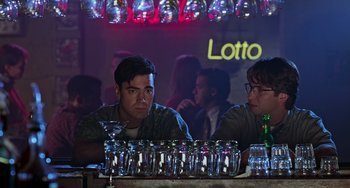 Movie still from “Office Space” (1999), directed by Mike Judge – A man sitting at a table with a lot of empty glasses; Medium shot, Low angle