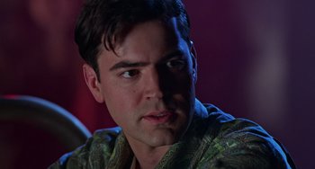 Movie still from “Office Space” (1999), directed by Mike Judge – A person wearing a green shirt; Close Up shot, Low angle