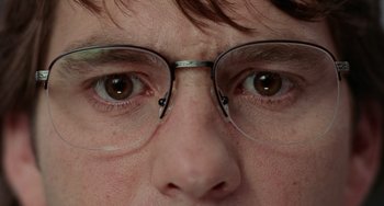 Movie still from “Office Space” (1999), directed by Mike Judge – A person wearing glasses; Extreme Close Up shot, High angle
