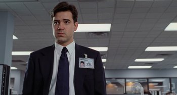 Movie still from “Office Space” (1999), directed by Mike Judge – A man in a suit and tie standing in an office; Close Up shot, Over the shoulder angle