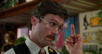 Movie still from “Office Space” (1999), directed by Mike Judge – A man in a suit and tie holding up a middle finger; Close Up shot, Over the shoulder angle