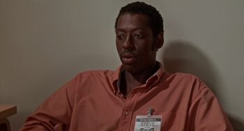 Movie still from “Office Space” (1999), directed by Mike Judge – A man in a red shirt is looking at the camera; Close Up shot, High angle