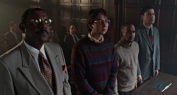 Movie still from “Office Space” (1999), directed by Mike Judge – A group of men standing next to each other in front of a wall; Medium shot, Low angle