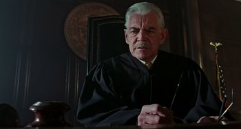 Movie still from “Office Space” (1999), directed by Mike Judge – An older man in a black robe holding a cane; Close Up shot, Low angle