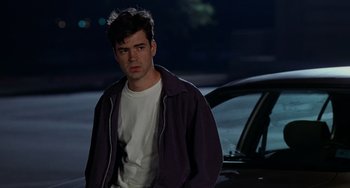 Movie still from “Office Space” (1999), directed by Mike Judge – A man standing in front of a car at night; Medium shot, Over the shoulder angle