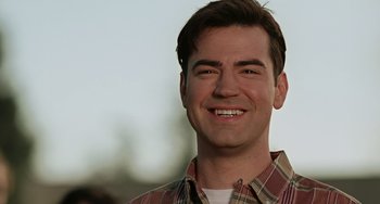 Movie still from “Office Space” (1999), directed by Mike Judge – A person wearing a plaid shirt smiling; Close Up shot, Low angle