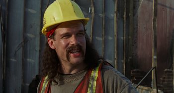 Movie still from “Office Space” (1999), directed by Mike Judge – A man with long hair wearing a hard hat; Close Up shot, Over the shoulder angle