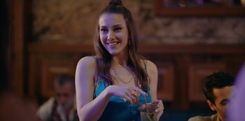 Movie still from “Oh Belinda” (2023), directed by Deniz Yorulmazer – A beautiful young lady holding a drink in her hand; Medium shot, Over the shoulder angle
