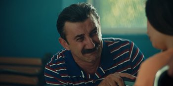 Movie still from “Oh Belinda” (2023), directed by Deniz Yorulmazer – A person wearing a striped shirt; Close Up shot, Low angle