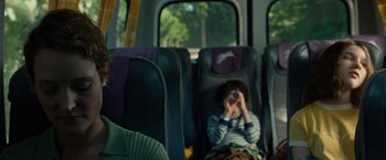 Movie still from “Old” (2021), directed by M. Night Shyamalan – A boy sitting on a bus with his hands behind his head; Close Up shot, Over the shoulder angle