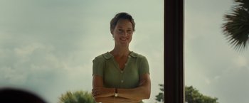 Movie still from “Old” (2021), directed by M. Night Shyamalan – A woman standing with her arms crossed in front of a window; Medium shot, Low angle