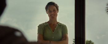 Movie still from “Old” (2021), directed by M. Night Shyamalan – A woman standing with her arms crossed in front of a sky background; Medium shot, Low angle