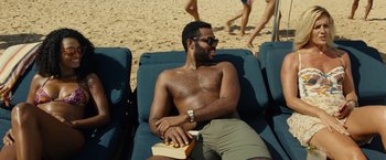 Movie still from “Old” (2021), directed by M. Night Shyamalan – A man sitting on a chair on the beach; Medium shot, High angle