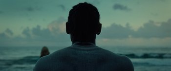 Movie still from “Old” (2021), directed by M. Night Shyamalan – A man is looking out over the ocean at dusk; Close Up shot, Over the shoulder angle