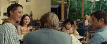 Movie still from “Old” (2021), directed by M. Night Shyamalan – Two people sitting at a table in a restaurant; Medium shot, Over the shoulder angle