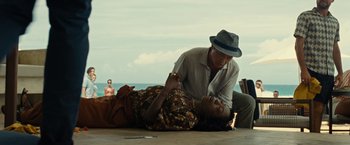 Movie still from “Old” (2021), directed by M. Night Shyamalan – A woman laying on the ground next to an older man; Medium shot, Low angle