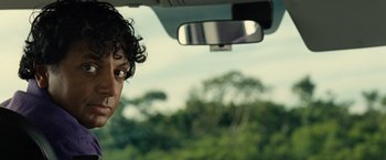 Movie still from “Old” (2021), directed by M. Night Shyamalan – A man with curly hair is looking out the window of a car; Close Up shot, Over the shoulder angle