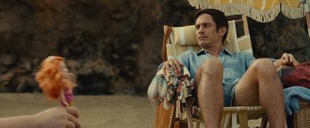 Movie still from “Old” (2021), directed by M. Night Shyamalan – A man sitting in a chair on the beach; Medium shot, High angle