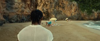 Movie still from “Old” (2021), directed by M. Night Shyamalan – A woman sitting on the beach looking out at the ocean; Medium shot, Over the shoulder angle