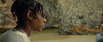 Movie still from “Old” (2021), directed by M. Night Shyamalan – A young man with dreadlocks looking into the distance; Close Up shot, Low angle